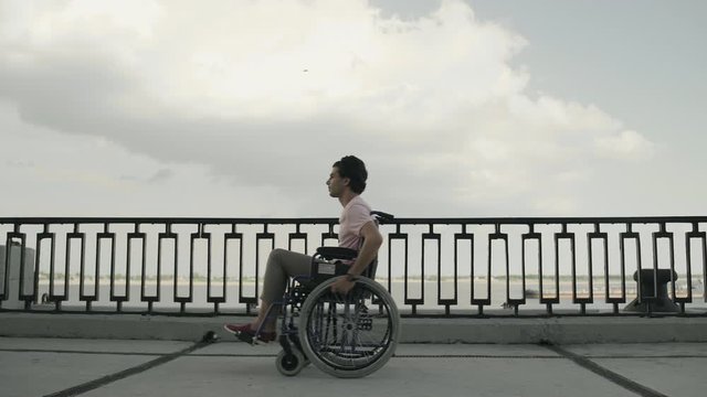 Man with paralysis of legs muscles is sitting in invalid carriage and riding. Ride from Right to Left