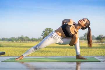 Young Asian playing and pose Yoga on the floor with nature rice field and blue sky background, Yoga Concept.