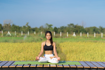 Young Asian playing and pose Yoga on the floor with nature rice field and blue sky background, Yoga Concept.