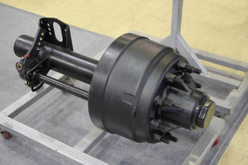 New semi trailer axle with brake drum on stand close up, truck transmission repair - obrazy, fototapety, plakaty