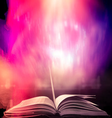 Open an old book with magical light magic on an ancient table in a dark room.