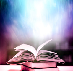 Open an old book with magical light magic on an ancient table in a dark room.