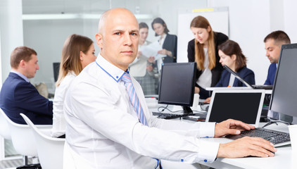 Fototapeta na wymiar Confident businessman concentrated on work with laptop in coworking space