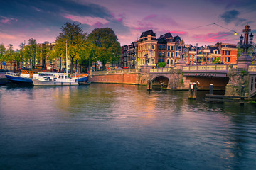 Dutch water canals with moored boats at sunset, Amsterdam, Netherlands