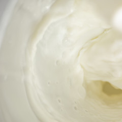 Square background with flowing white milk, soft focus