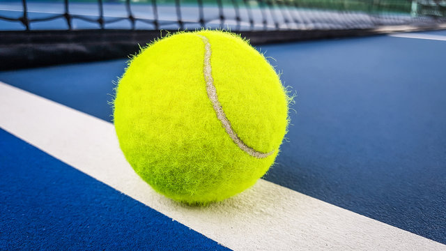 Close-up shots of tennis balls in tennis courts With a mesh as a blurred background And the light shining on the ground makes the image beautiful
