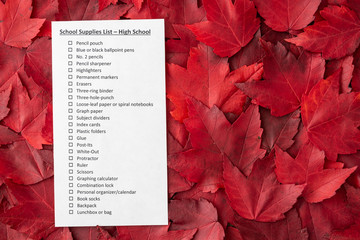 Back to school, school supplies list, high school, on a bed of red fall leaves