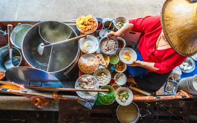 Papier Peint photo autocollant Bangkok Vue de dessus vieille femme cuisinant une soupe de nouilles thaïlandaise à la manière de Tom Yam sur un bateau de tradition thaïlandaise sur un marché flottant local, célèbre cuisine de rue traditionnelle thaïlandaise pour les touristes voyageant à Bangko