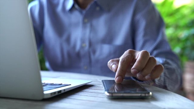 Working on computer and cell phone with home and garden background. Work from home or flexi work concept.