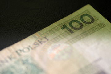 One hundred Polish zloty banknote on a dark surface close-up. Money background green color toned