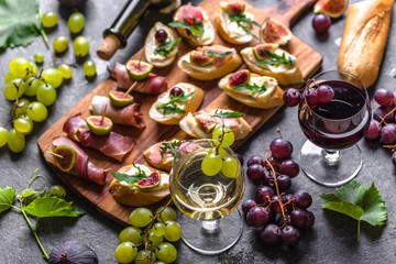 Traditional spanish tapas, wine snack set - food from spain or italian antipasti: bruschetta with cheese, meat and fruits. Cold appetizers and wine glasses. - obrazy, fototapety, plakaty