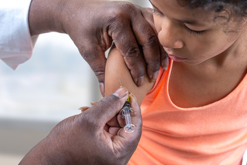 Little suspicious girl get an injection, vaccination at hospital