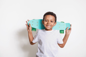 Cute African-American boy with skateboard on white background © Pixel-Shot