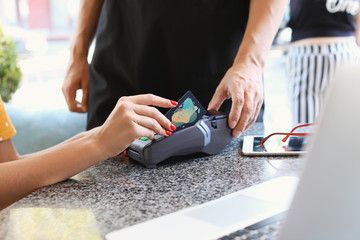 Young woman paying by credit card in cafe