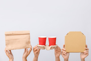 Many hands with food containers and cups on light background