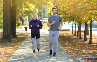 Fototapeta premium Sporty young couple running in park