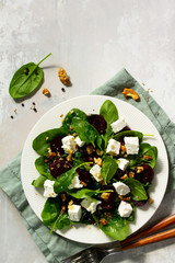 Vitamin snack. Salad with spinach, feta cheese, beetroot and walnut, vegetable oil sauceon a concrete table.