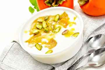 Dessert of yogurt and persimmon in bowl on board