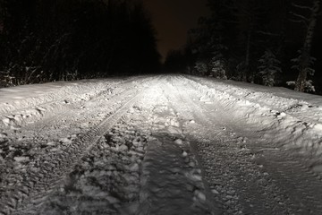 Winter road at night. Light of car headlight  on the road