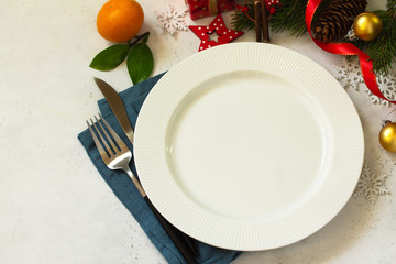 New Year, Christmas dinner, table setting. Christmas table with plate, silver and Fir branch on a white concrete table. Copy space.