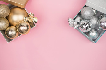 Gold and silver gift box with gold and silver Christmas balls on pink background,copy space, flat lay