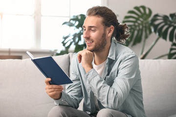 Young man with hearing aid reading book at home