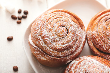 Plate with tasty cinnamon buns on table, closeup