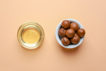 Tasty macadamia nuts with oil on color background