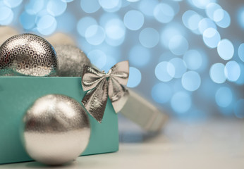 Blue box with silver Christmas balls on the background of blue bokeh lights