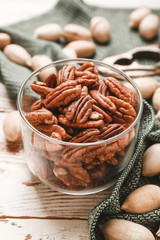 Glass with tasty pecan nuts on wooden background