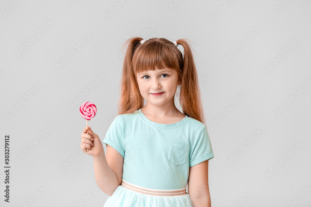 Wall mural cute little girl with lollipop on light background