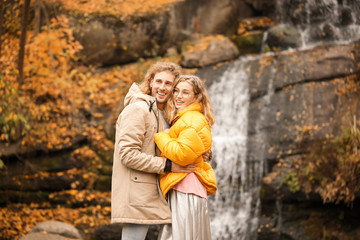 Young couple near waterfall in park on autumn day