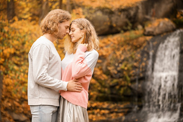 Fototapeta premium Young couple near waterfall in park on autumn day