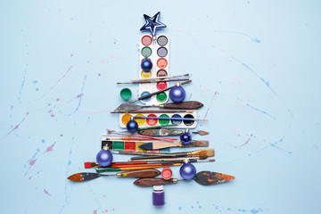 Beautiful Christmas tree made of painter tools on color background