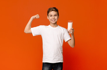 Cheerful teenage boy demonstrating biceps after drinking milk