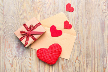 Gift box for Valentine's Day, envelope and red hearts on wooden background
