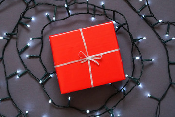 Red gift box with silver ribbon and glowing led garland Photo