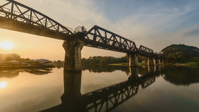 4K Time lapse of sunrise over railway crossing river Kwi. Kanchanaburi, Thailand. Historical raiway during world war II. Camera pan up.
