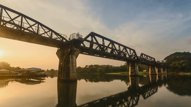 4K Time lapse of sunrise over railway crossing river Kwi. Kanchanaburi, Thailand. Historical raiway during world war II. Camera zoom out.
