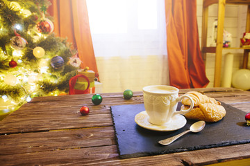 Mug with hot chocolate on a wooden table with Christmas decorations on a background of the Christmas tree
