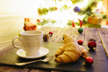 Mug with hot chocolate on a wooden table with Christmas decorations on a background of the Christmas tree