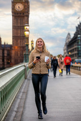 Blonde Touristin mit Telefon und Kaffee in der Hand läuft vor dem Big Ben Turm auf der Westminster...