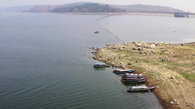 Aerial zoom into parked boats and lake with dry shoreline, dolly in