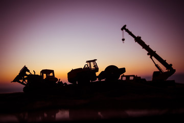 Abstract Industrial background with construction crane silhouette over amazing sunset sky. Mobile crane against the evening sky. Industrial skyline. Selective focus