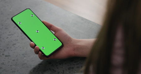 young woman holding smartphone over terrazzo countertop