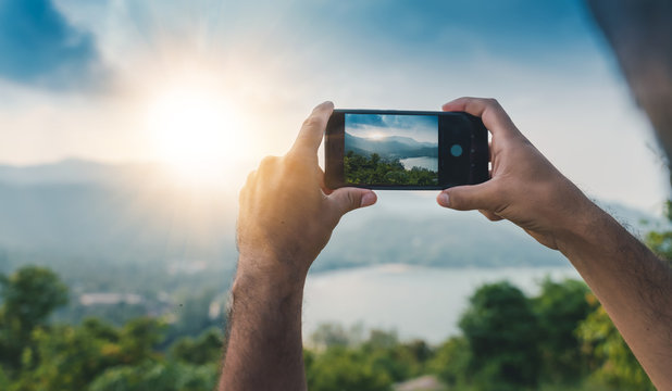 Smartphone hands shooting a beautiful landscape with sunset, travel concept and photography