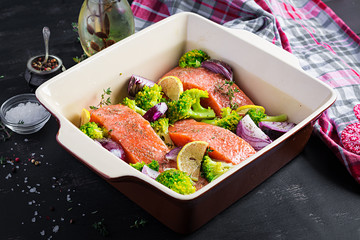 Salmon, broccoli and red onion slices are prepared in a baking dish.