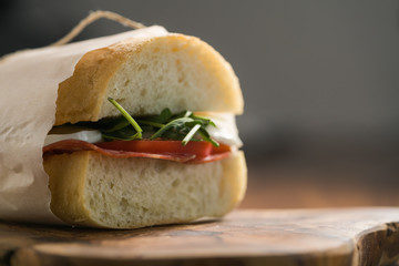 closeup ciabatta sandwich with salami and mozzarella cheese on walnut table