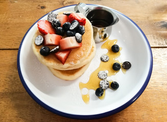 pancake with strawbery blueberry and honey on wooden table.