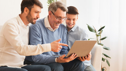 Elderly Man Using Laptop Sitting Between Son And Grandson Indoor